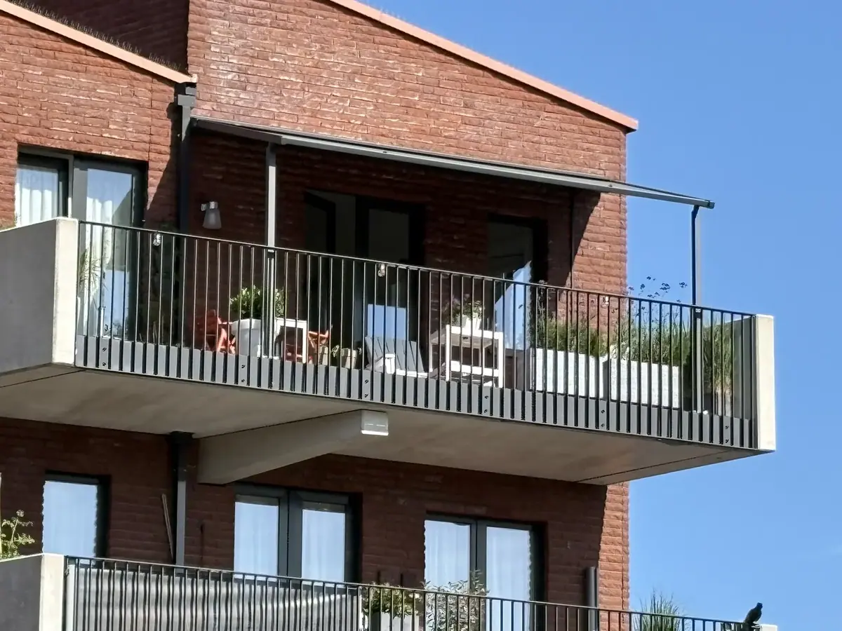 Knikarmscherm met steunpoot naar de balustrade op een balkon in Waterpark, Heemstede