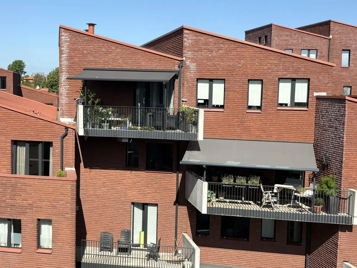 Twee knikarmschermen uitgeklapt boven de balkons van Waterpark in Heemstede